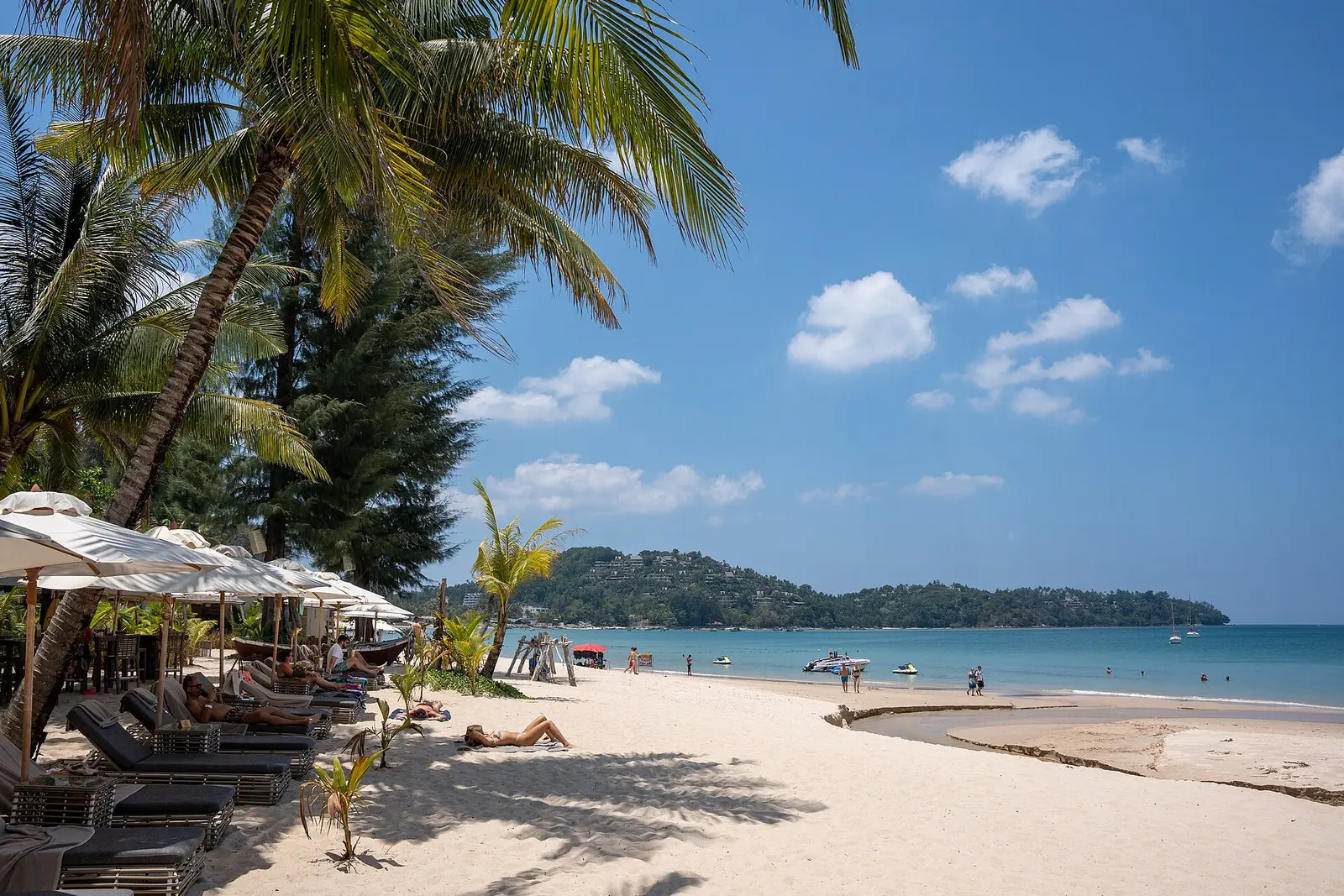Bang Tao Beach in Phuket with sun loungers, palms and a calm blue bay