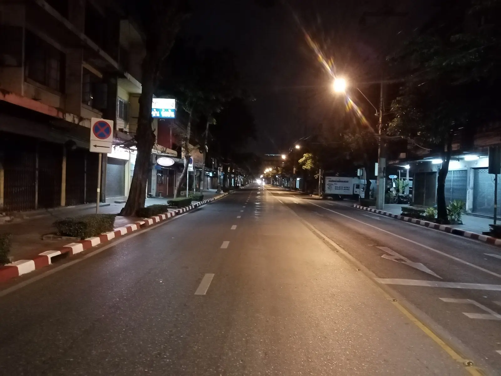 Banthat Thong Road in Bangkok at night with shopfronts and street lights