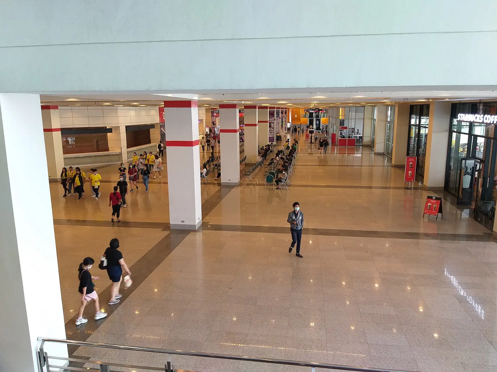 Visitors walking through a bright concourse inside the BITEC exhibition centre in Bang Na