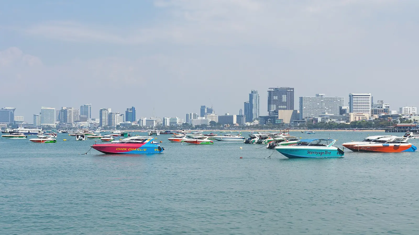 Pattaya skyline across the bay with colourful speedboats moored in the foreground