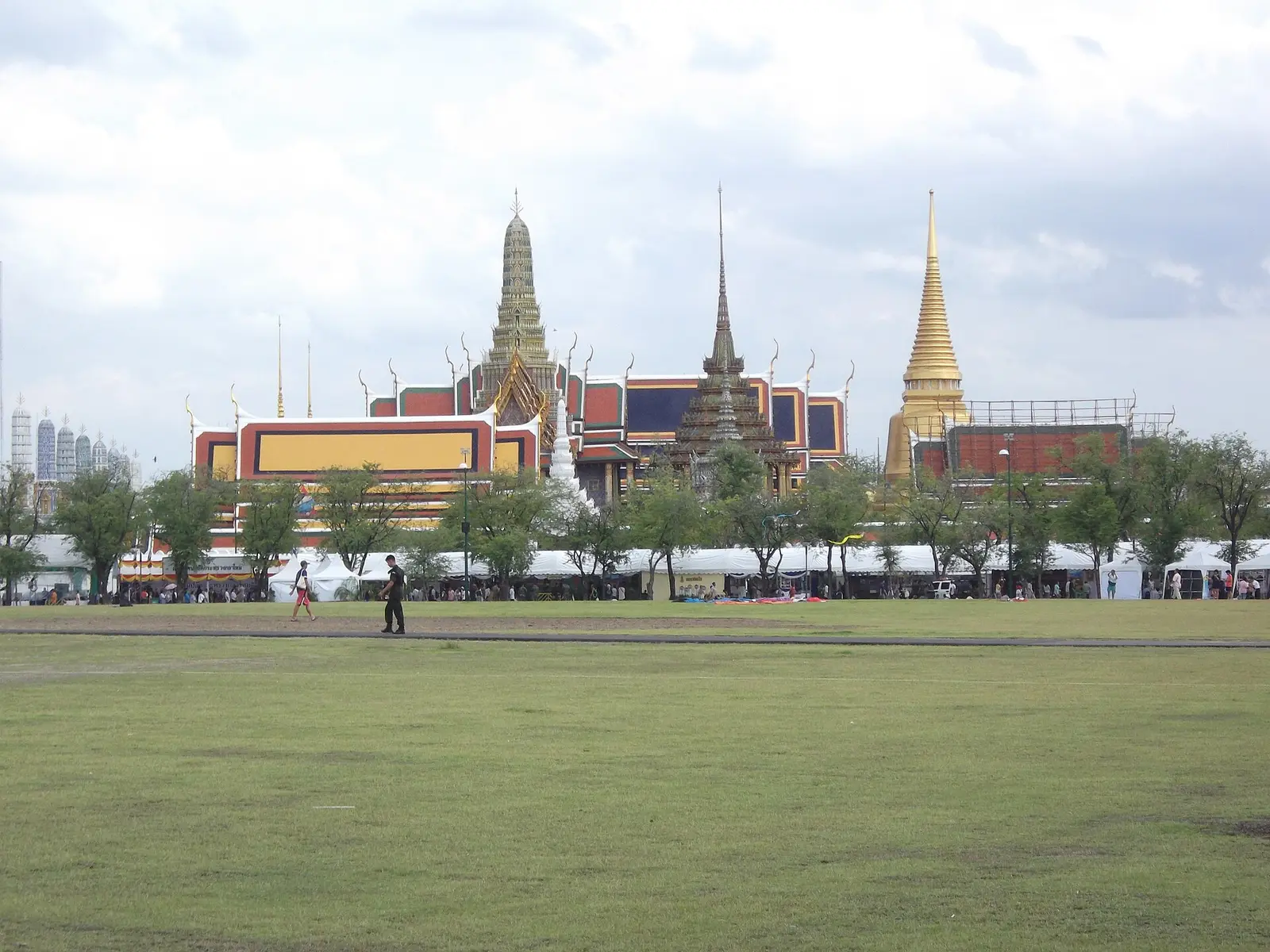The open lawn of Sanam Luang with the Grand Palace and temple spires beyond the trees