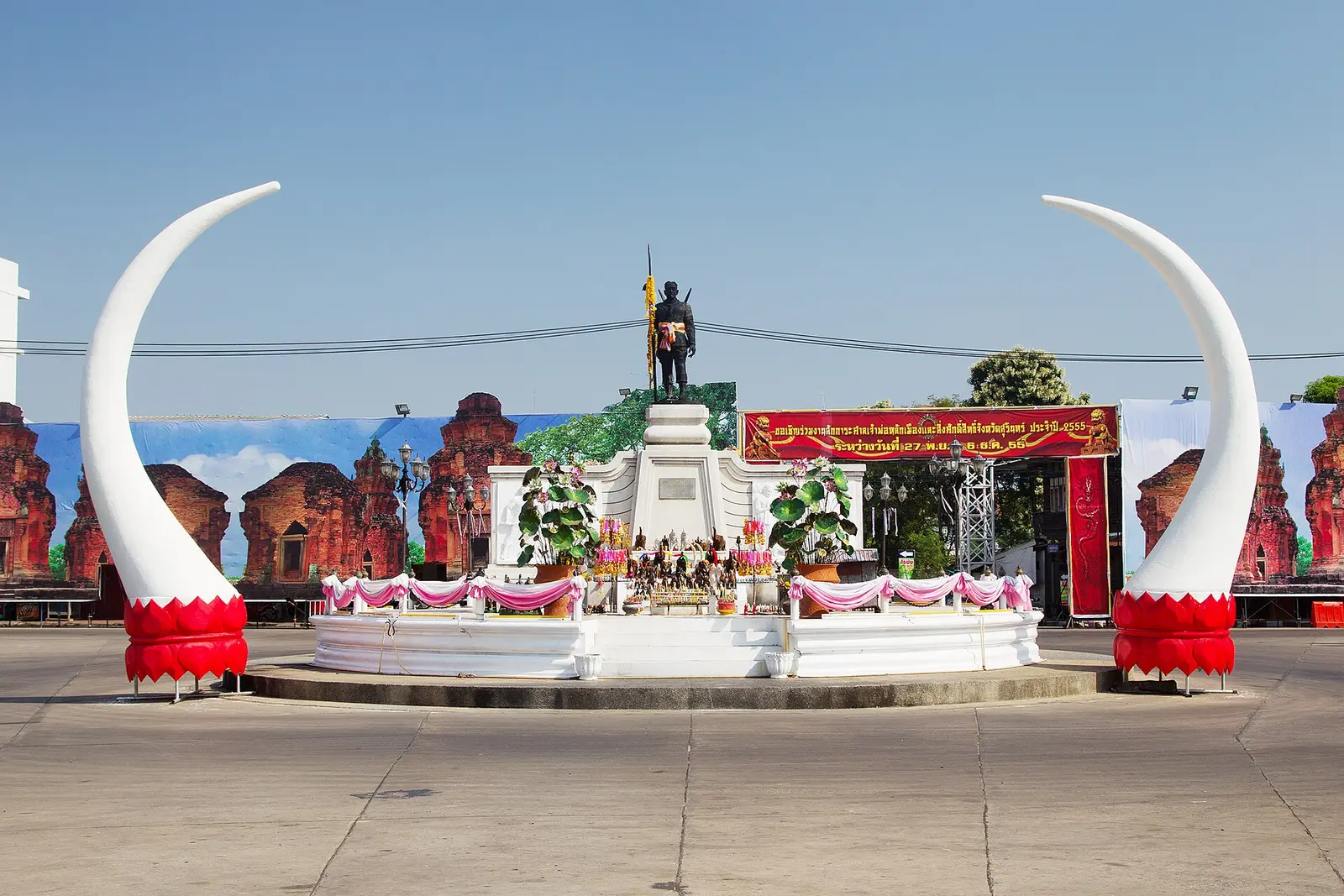 Monument in Surin town framed by two giant white elephant tusks under a blue sky